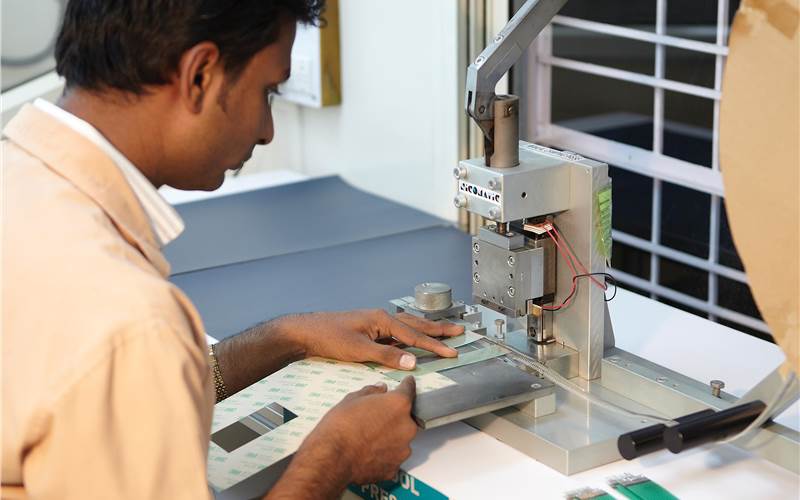 A printed circuit is being crimped to attach connectors on a hand-press crimping machine