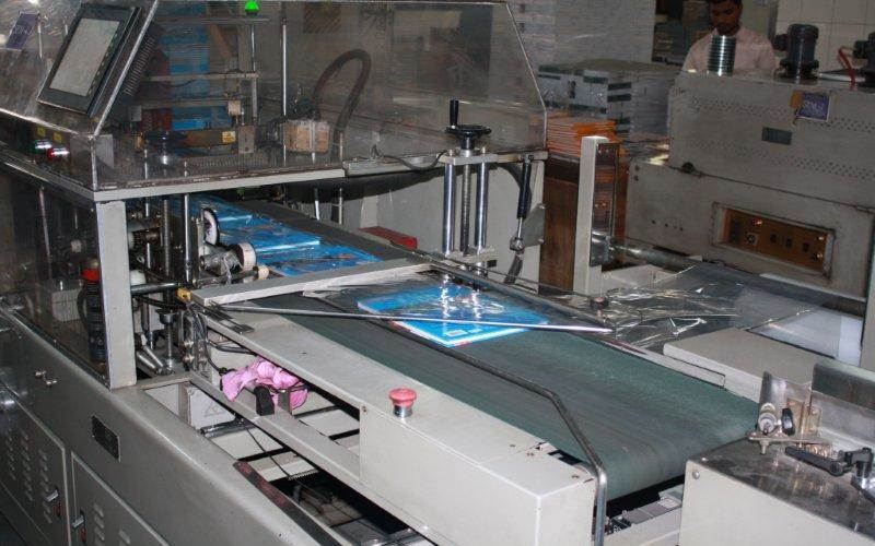 Hard-case books on a conveyor belt and shrink-wrapped