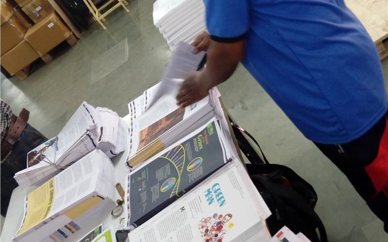 An employee compiling sheets to make a collection for a magazine